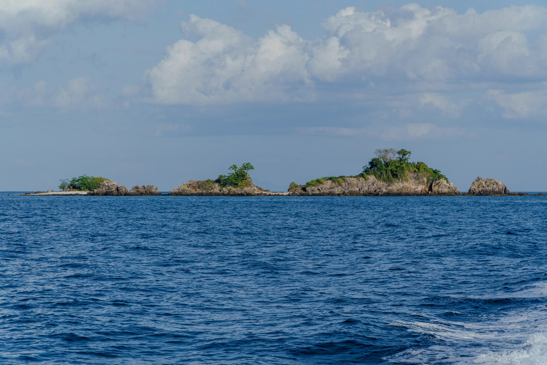 Islands dot the calm sea with fluffy clouds above.